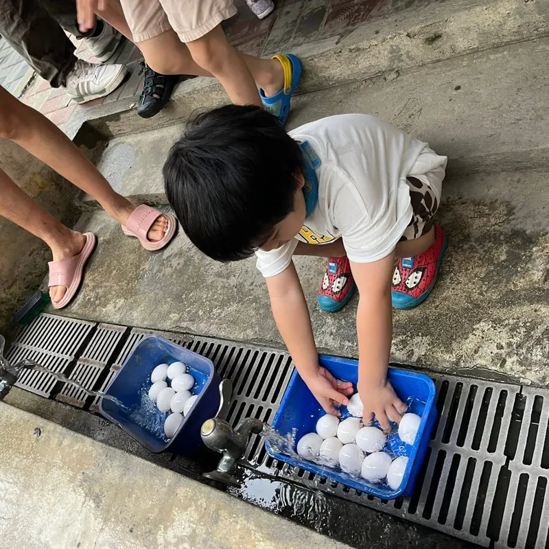 孩子在葵海農場的戶外活動中提著水桶走過泥灘,尋找溼地生物